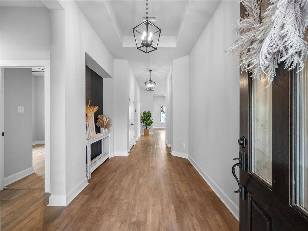 Upon entering the home, you're greeted with custom chandelier anchored in the tasteful coffered ceiling & upgraded entry niche.