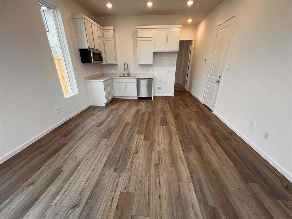 This bright and open kitchenette, part of the NextGen suite, offers a convenient and functional space for preparing meals. It seamlessly blends with the living area, featuring modern cabinetry and ample natural light from multiple windows.