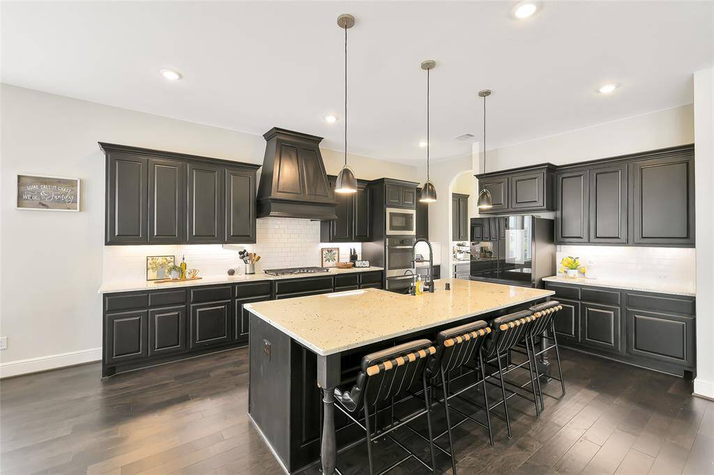 Sleek central island anchors the kitchen, framed by striking pendant lights—perfect for gathering and food prepping