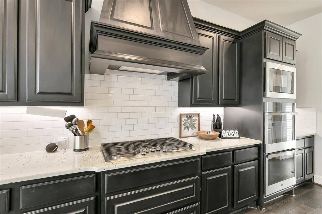 Statement vent hood, classic subway tile, and a pro-style gas cooktop blend form and function for a chef-worthy centerpiece.