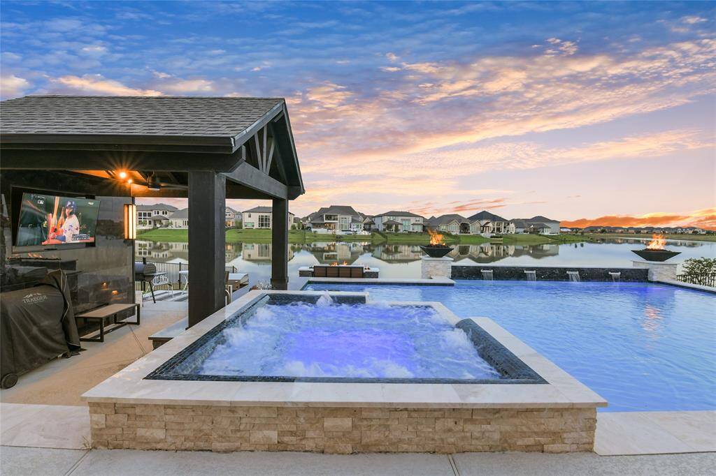 This large pool with four waterfall features, spa, two fire bowls, and swim up bar to the sunken Summer Kitchen all overlook beautiful Towne Lake.