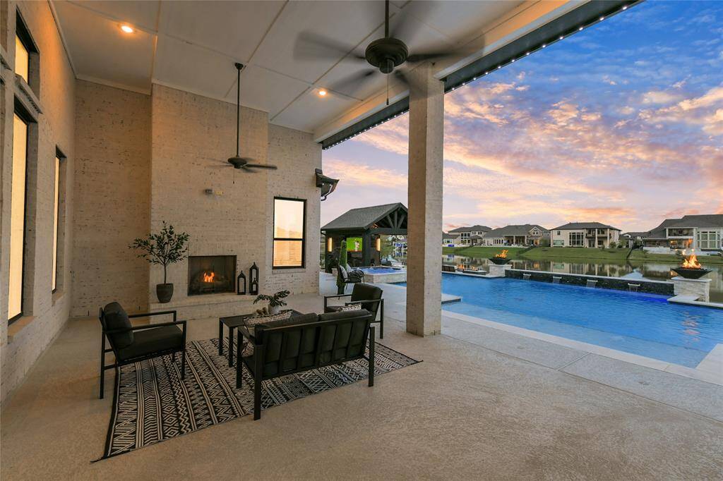 Spacious covered back patio with floor to ceiling brick fireplace and two ceiling fans.