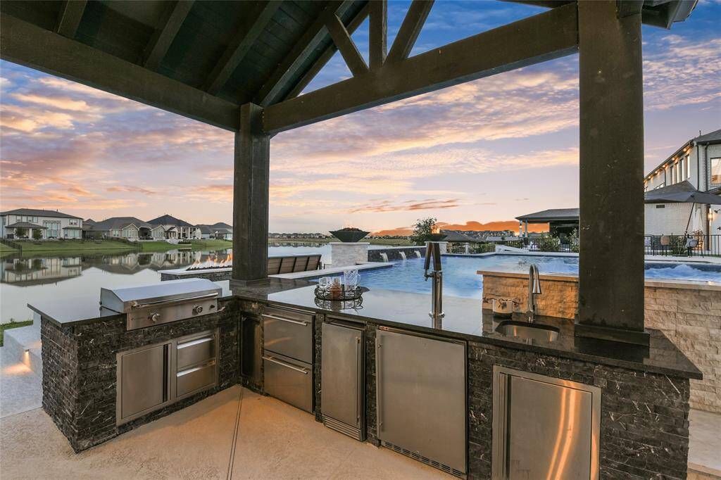 Fully outfitted summer kitchen with stone base, granite countertops, grill, refrigerator, ice maker, kegerator, sink and lots of storage.