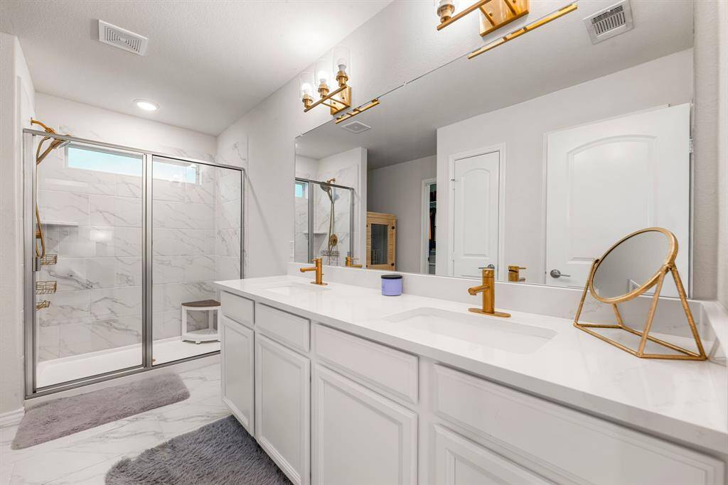 This primary bathroom is definitely move-in ready! Featuring a dark framed walk-in shower with tile surround, separate garden tub for soaking after a long day with custom tile detailing, dark stained cabinets with light countertops, spacious walk-in closet with shelving, high ceilings, custom paint, sleek and dark modern finishes.