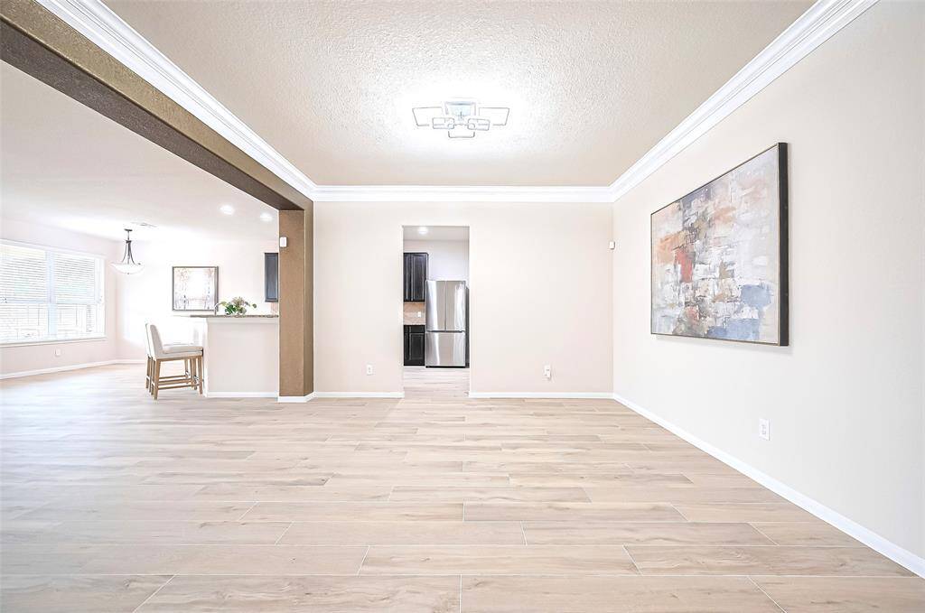 A modern chandelier hangs gracefully above the dining space, enhancing and casting a warm glow throughout the space