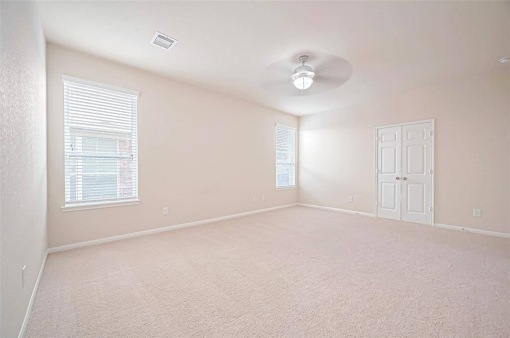 This spacious master bedroom offers a bright and inviting retreat, enhanced by plenty of natural light and a light beige new carpet