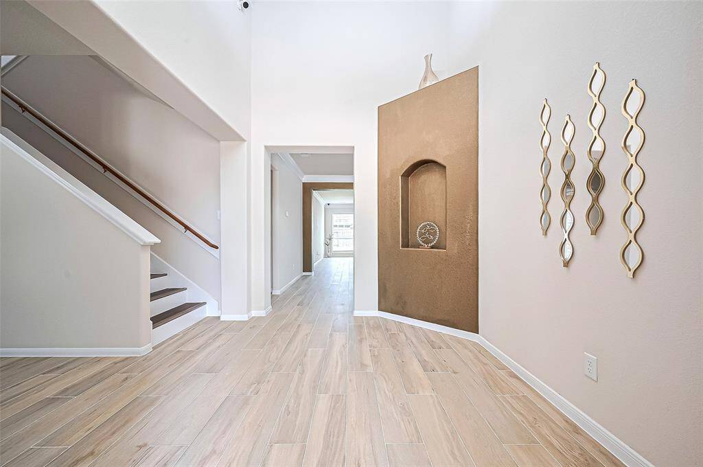 Grand two-story entrance featuring luxurious gold-toned wall exudes elegance and sophistication, making an unforgettable first impression