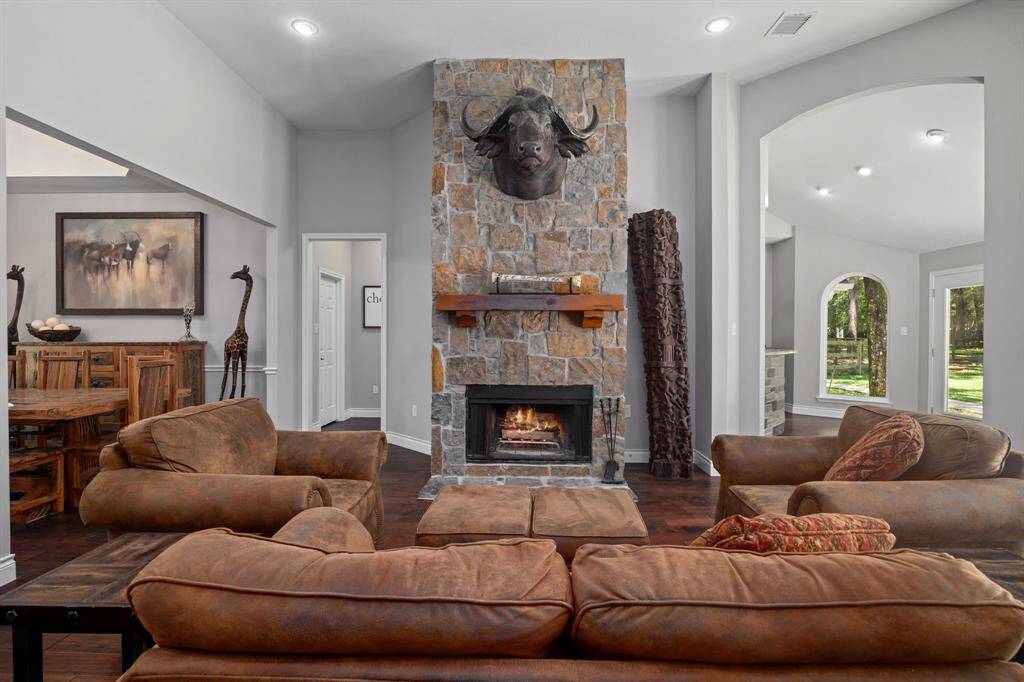 Another view of this amazing living room featuring a cozy floor to ceiling stone fireplace, wood mantle & wood burning fireplace with loads of natural light.