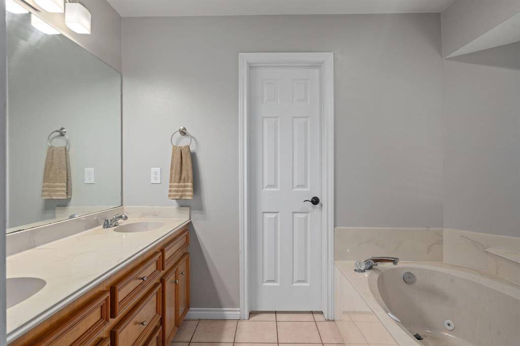 This bathroom features a large vanity with dual sinks and a relaxing jetted bathtub