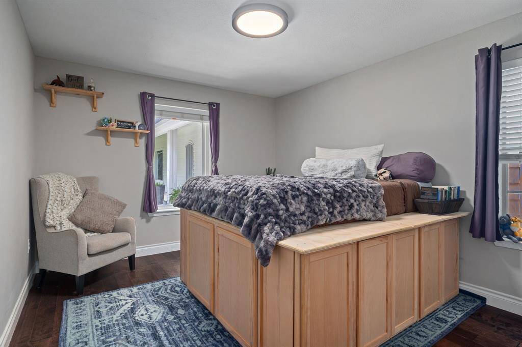 Cozy and inviting secondary bedroom featuring ample natural light & wood flooring
