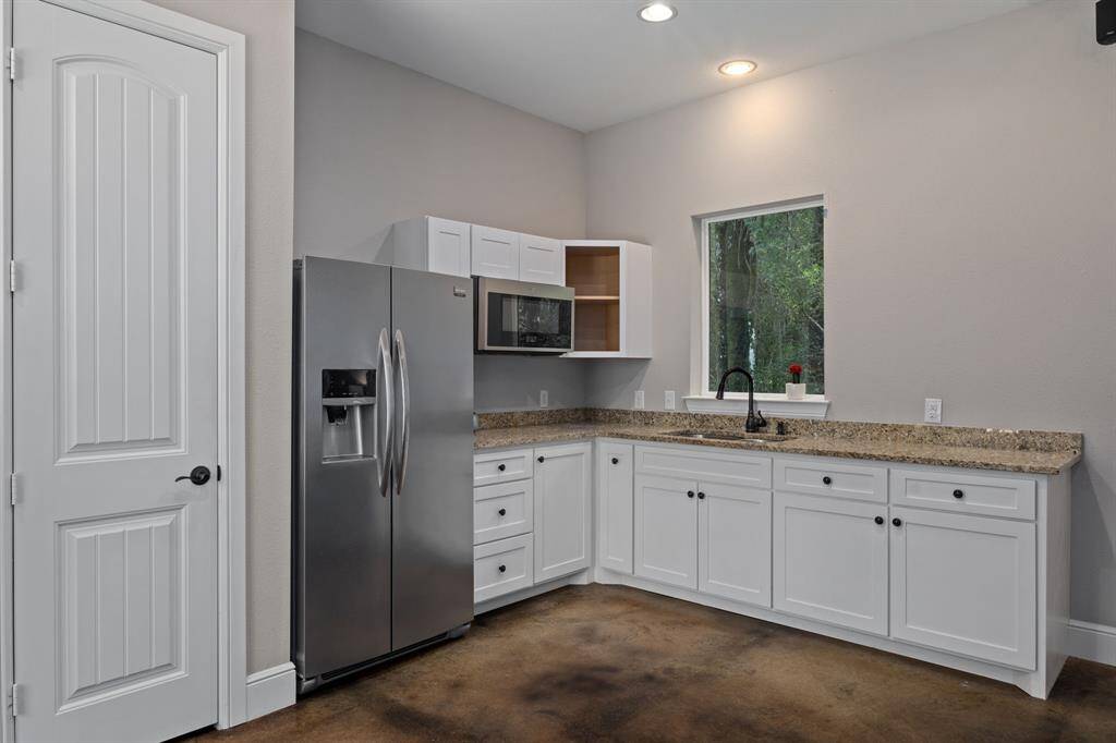 This Guest House includes a kitchenette with stainless steel fridge, white cabinetry. granite countertops with nice storage cabinets. It has a convection microwave and large pantry/storage and enough space for a small table for dining