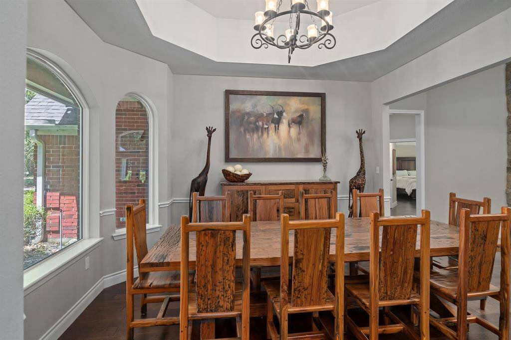The dining room features an elegant chandelier, and large arched windows providing ample natural light.