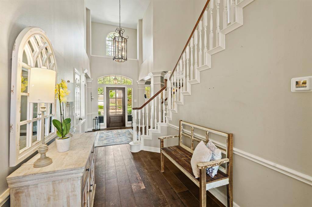 This inviting entryway features high ceilings, a grand staircase, and abundant natural light. The space is elegant, creating a warm and welcoming atmosphere.