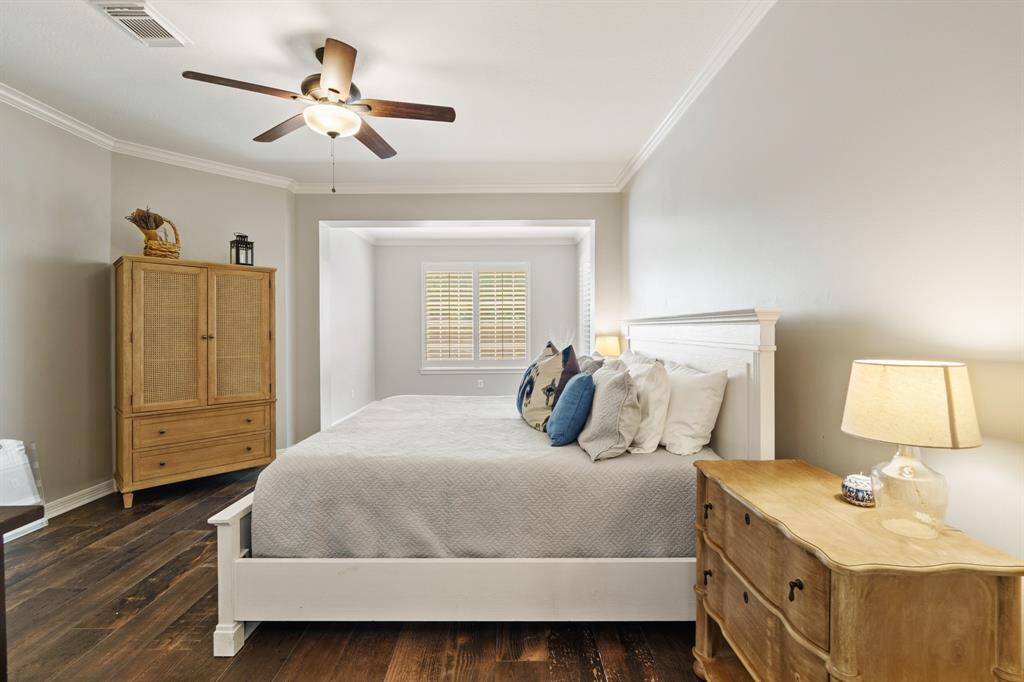 Another view of the charming bedroom with tile wood like floor and crown molding. Features a large window with shutters overlooking the POOL/SPA providing natural light.