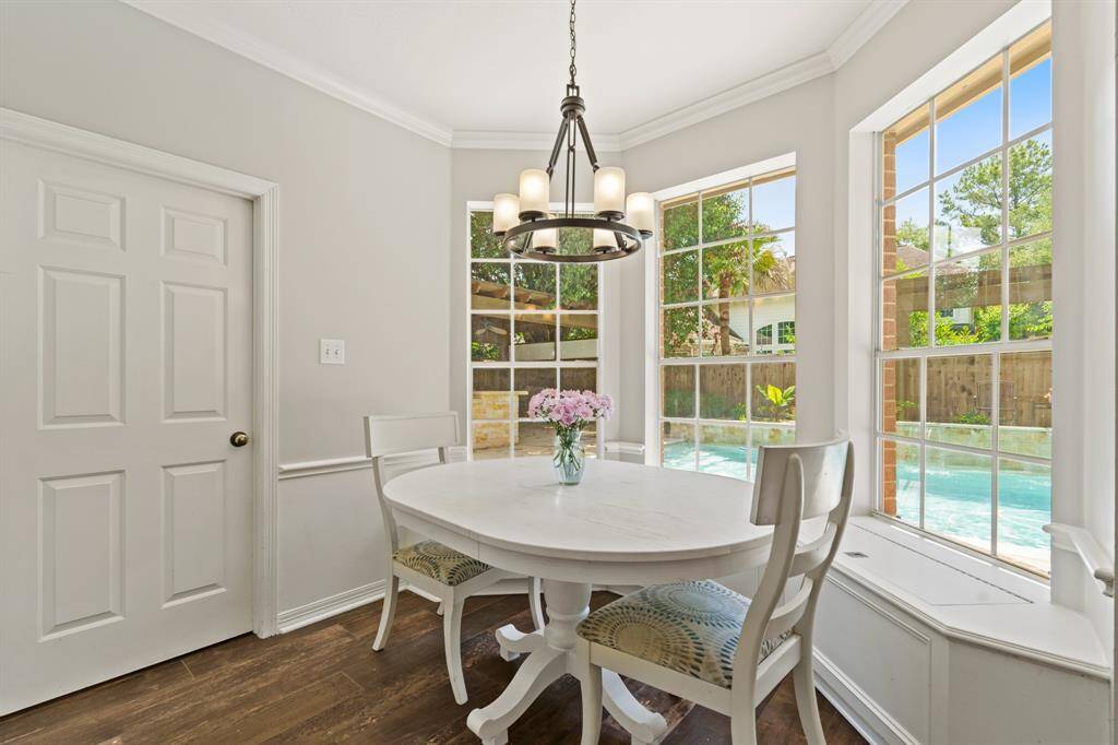 Bright and inviting breakfast nook with large windows offering POOL views. Features an elegant chandelier, and wood like tile flooring, creating a perfect spot for morning coffee.