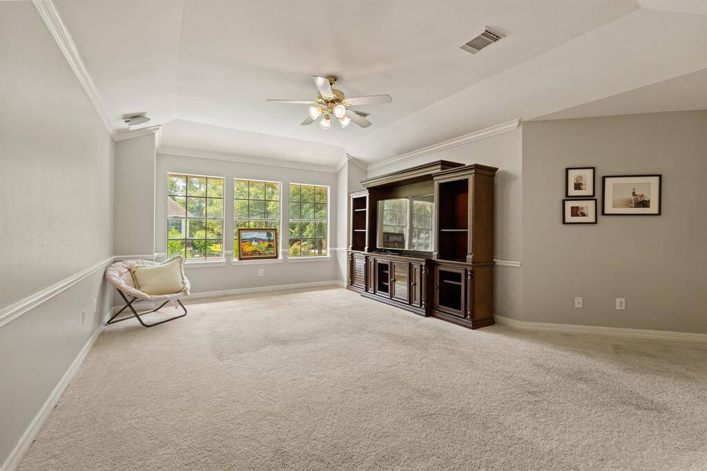 This nice sized game room or flex space has a large windows providing ample natural light and crown molding. It includes an entertainment center and has carpeting, making it a comfortable living space.