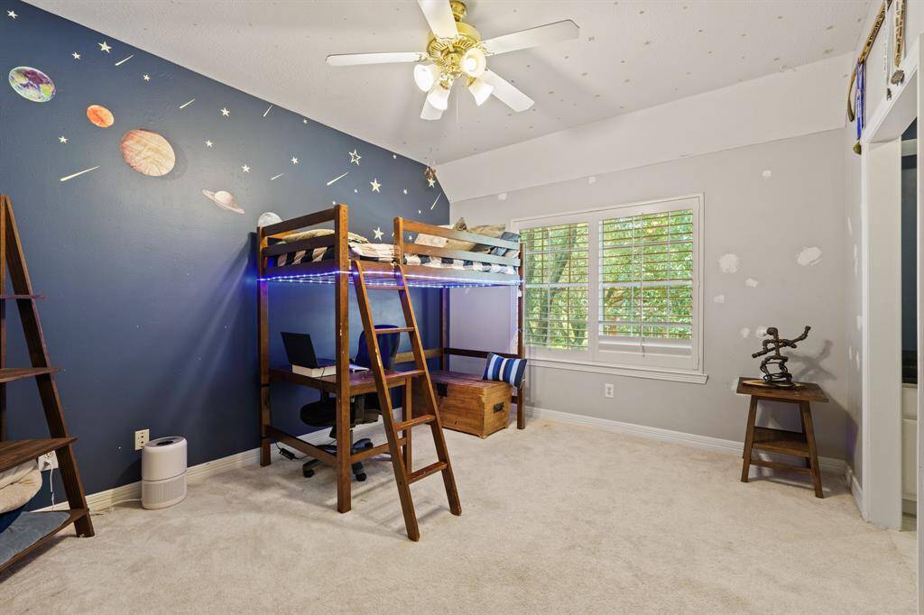 This is a sizeable secondary bedroom space featuring a large walk-in closet and a window with shutters that offers a view of trees. Jack and Jill bath with private vanity area.