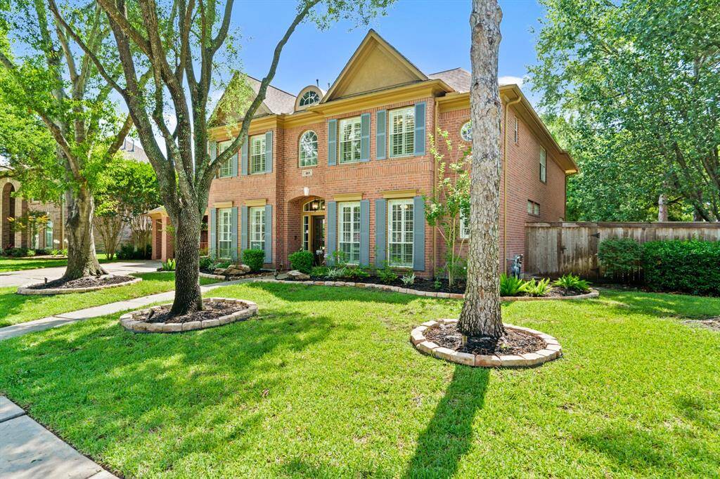 This is another view of a charming two-story brick home with mature trees.  A welcoming pathway leads to the front entrance, adding to the home's curb appeal.