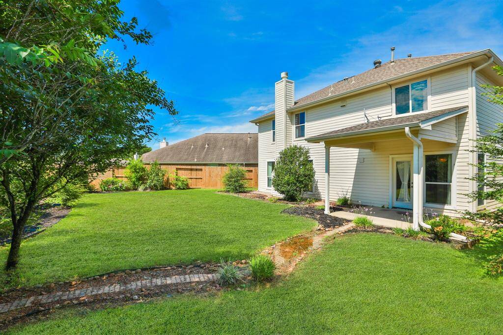 A spacious backyard boasts a meticulously maintained lawn and beautifully landscaped garden beds. The two-story home includes a covered patio, offering an inviting space for outdoor relaxation. Enclosed by a secure fence, the area ensures both privacy and peace of mind.