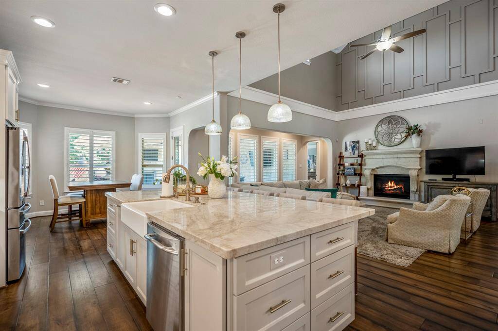 Taj Mahal Luxury Quartz countertops gleam under the pendant lighting, the unique stone is quarried in Brazil, notice the white porcelain farmhouse sink.