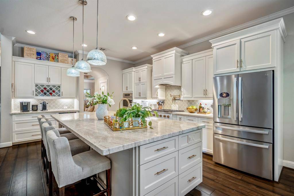 The island kitchen offers the convenience of a pot filler, and six burner gas range and double ovens surrounded by an abundance of beautiful cabinetry.