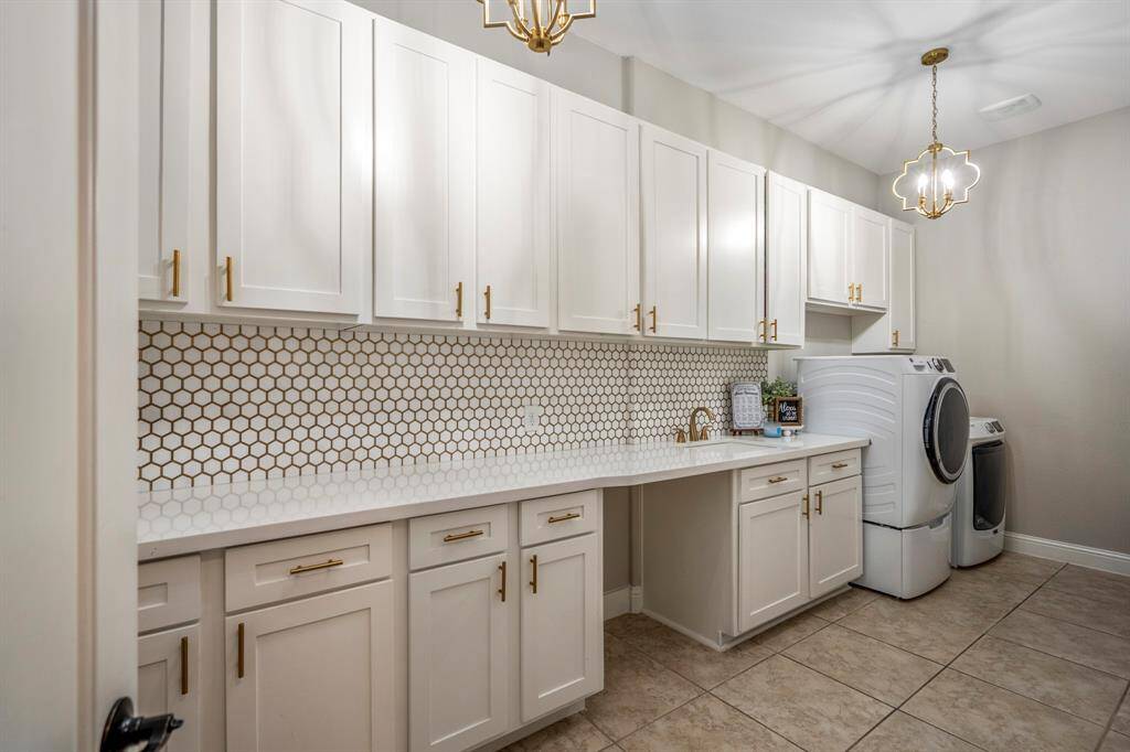 The huge laundry room offers a desk area, plenty of cabinetry, sophisticated lighting, maintenance easy tiled floors and beautiful backsplash.