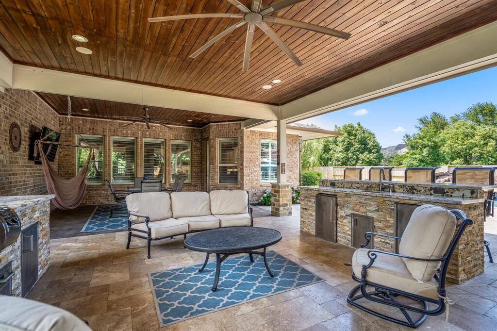 This patio is built to maximize outdoor entertaining with an outdoor kitchen accompanied the wood beaded ceiling with fans, stacked stone fireplace with mounted TV and plenty of covered seating complete the design.