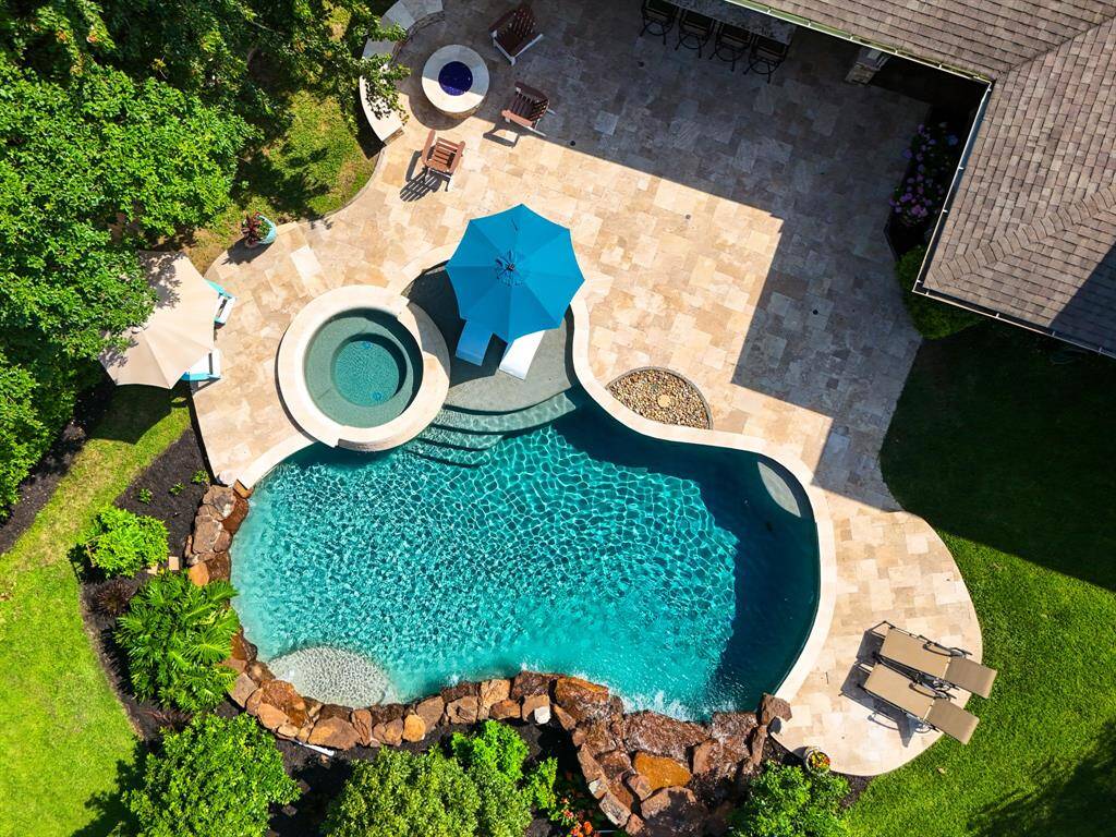 An overhead view of the stunning pool with tanning ledge, stacked stone raised spa, travertine decking, separate fire pit with seating situated on a large pie shape lot, recently replaced fence and your have the added bonus of never losing power with a 24-kW generator. This is the one is special!