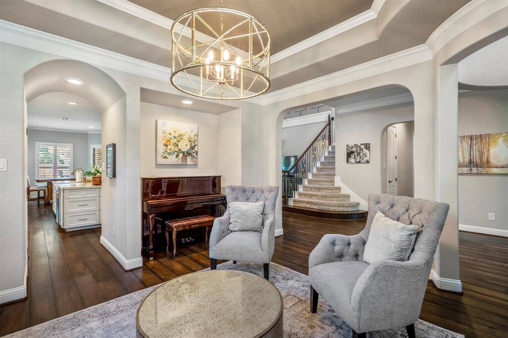 The formal living room has many upgraded quality features, with a stacked tray ceiling, arches, crown moldings, upgraded lighting and alcoves.