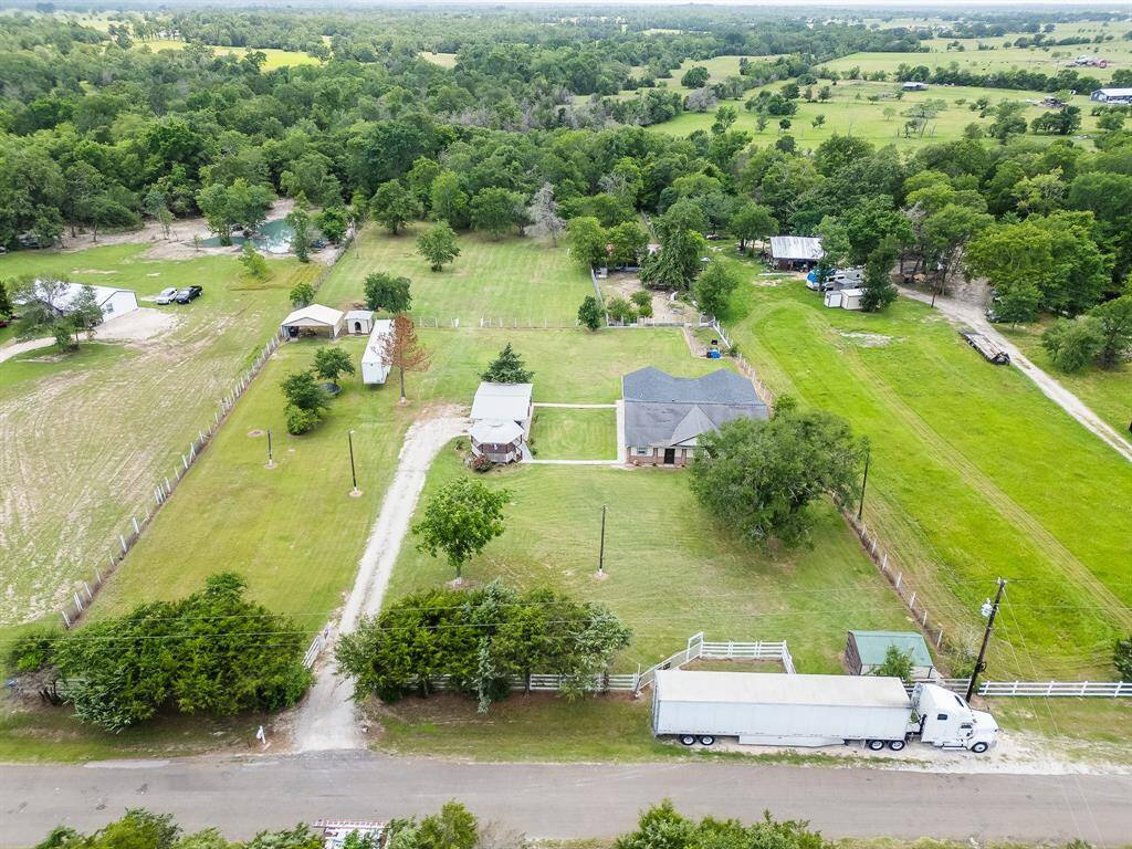 Front aerial angle highlighting the fenced entry, long driveway, and beautiful land features.