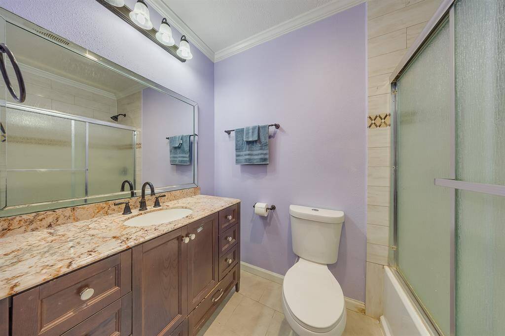 Updated bathroom with granite countertop, elegant lighting, and tiled shower—move-in ready and designed for daily comfort.