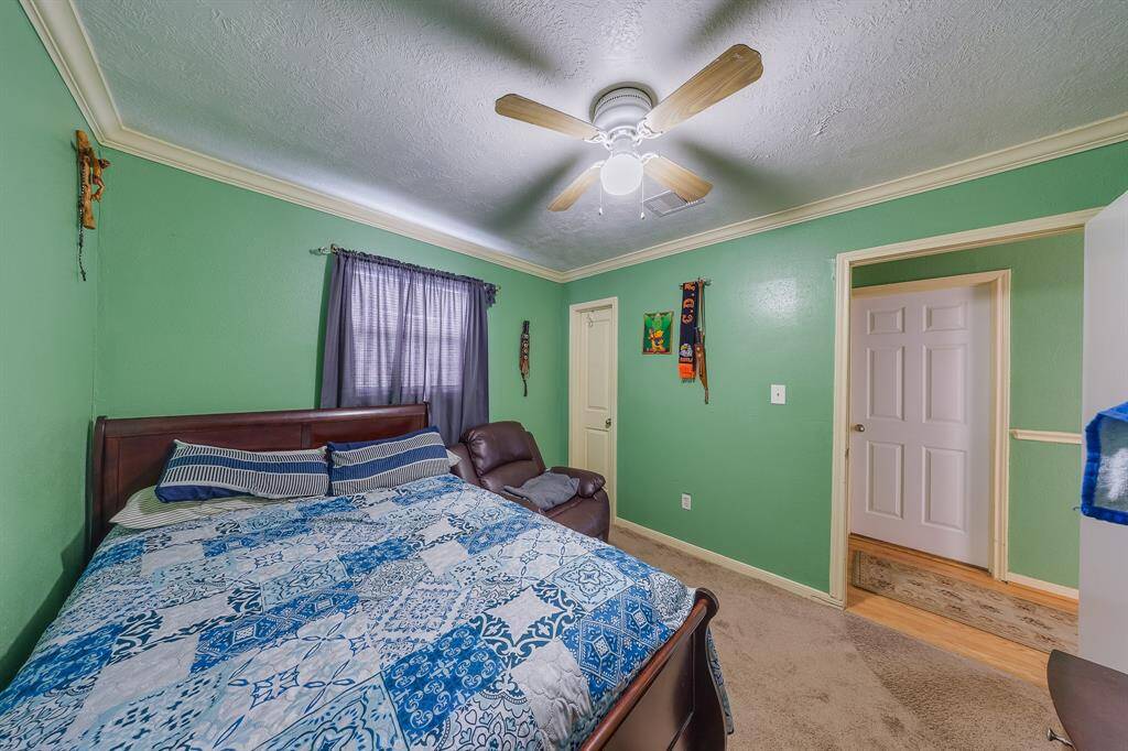 Cozy bedroom with deep green walls, crown molding, and natural light—perfect for rest or reading.