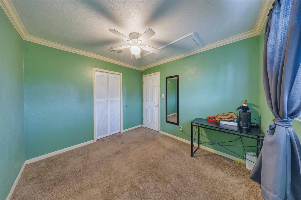 Bright bedroom with workspace, closet, and window—perfect for a home office or guest room setup.