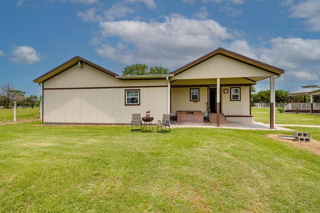 Covered back porch with seating area and BBQ space—ideal for weekend cookouts and quiet mornings.