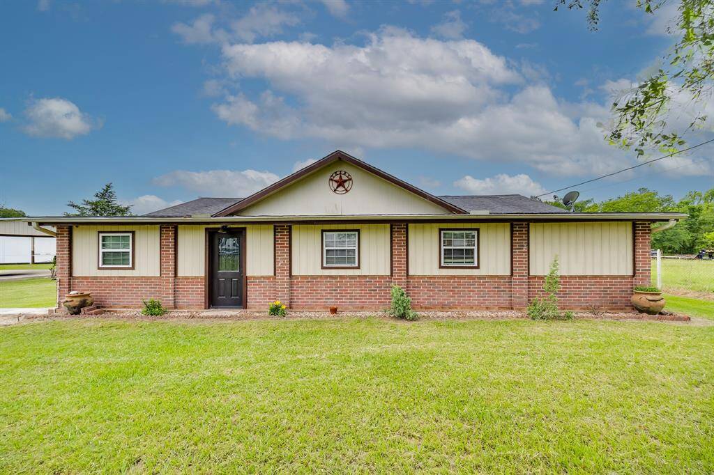 Clean, symmetrical front exterior with Texas star detail and a wide grassy lawn ready for play or pets.