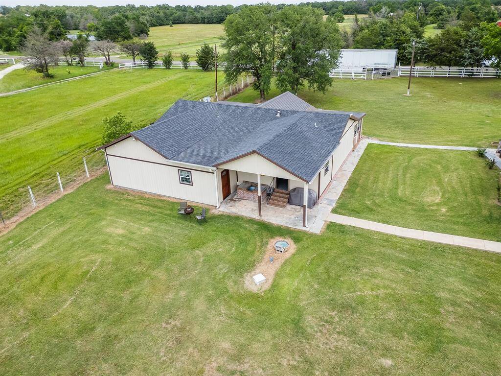 Backyard angle of the home showing the covered patio and spacious green area.