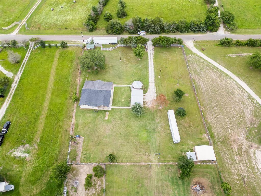 Drone view of full property layout—house, gazebo, shed, and open land beautifully organized and fenced.