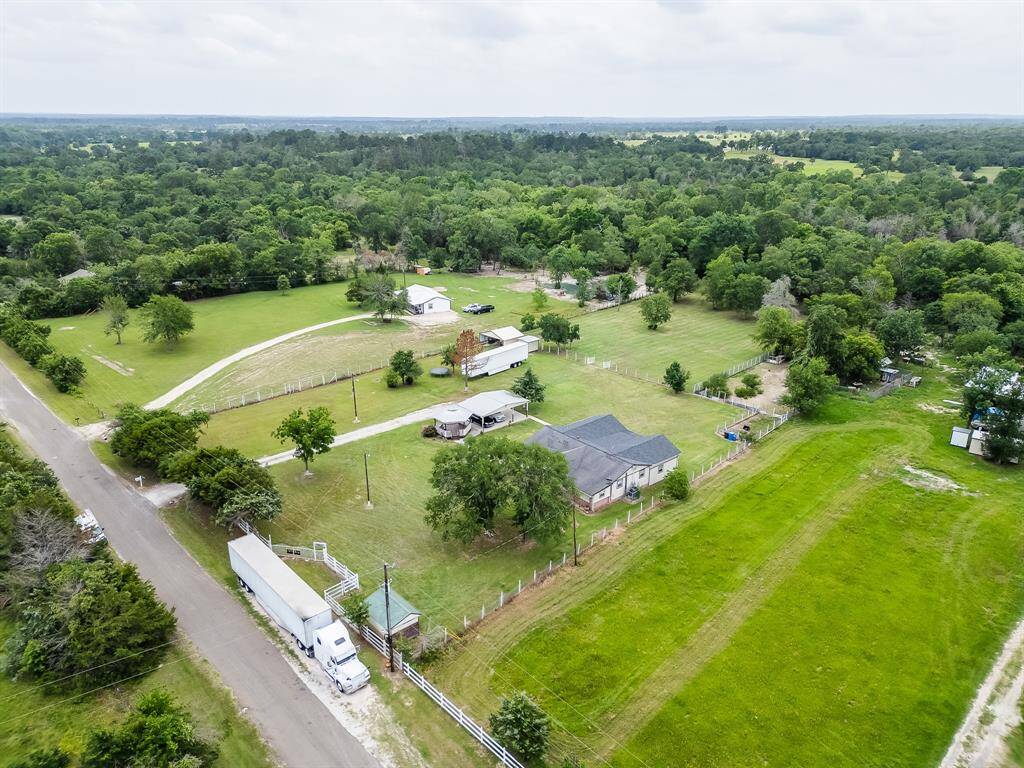 Wide aerial view showcasing the lush green surroundings and full layout of the property.