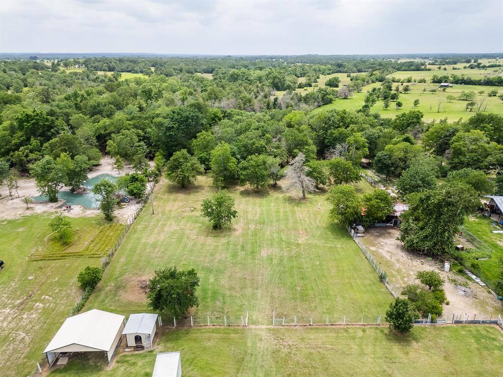 Rear aerial view highlights clear open skies, lush trees, and tranquil setting ready for your outdoor vision.