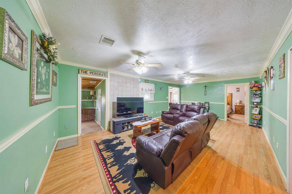 Spacious living room with wood floors, crown molding, and natural flow into bedrooms and bonus spaces.