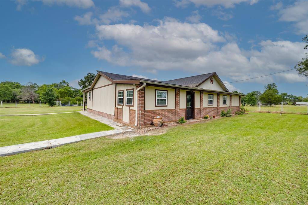 Spacious side yard with mature trees, fenced boundary, and charming brick accents along the home.