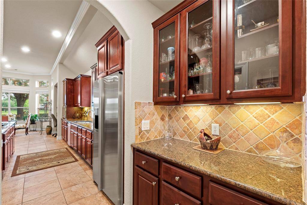 The kitchen is a host’s dream with designated bar area. Enjoy your favorite beverage with ease as you admire the glass cabinetry adding a touch of sophistication to any occasion.