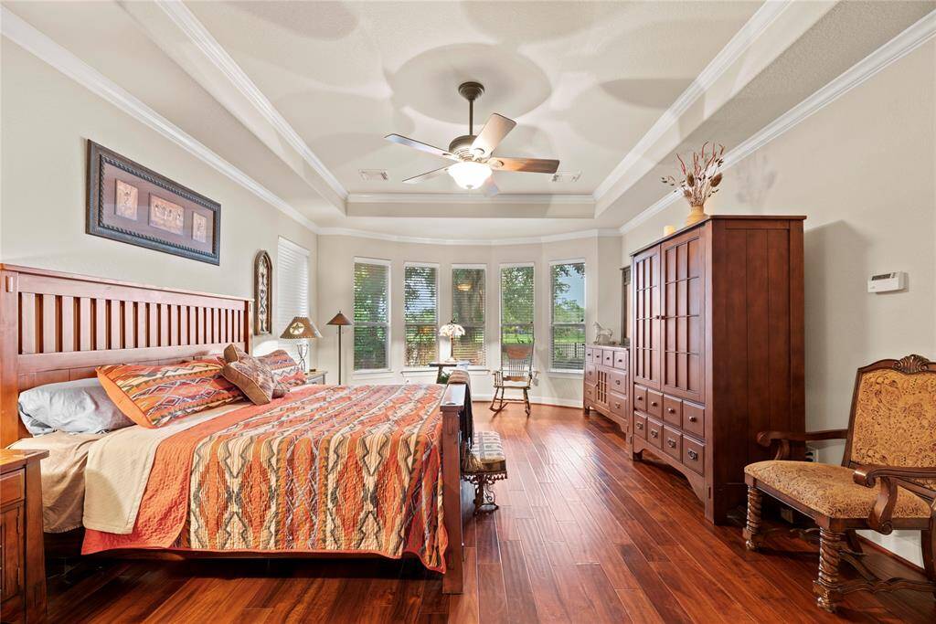 Very ample primary suite with double crown molding and wood floors.