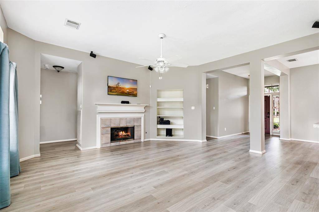 The living room boasts built-in shelves, a double sided fire place, surround sound, and natural light.