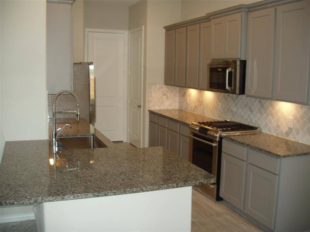 Kitchen view, granite counters and stainless steel appliances.