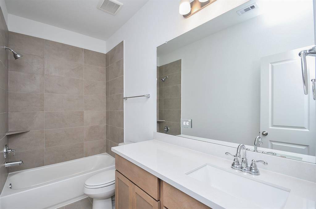 Delicate overhead lighting, wall mirror and a simple modern vibe deliver all the comforts you need in a secondary bathroom.