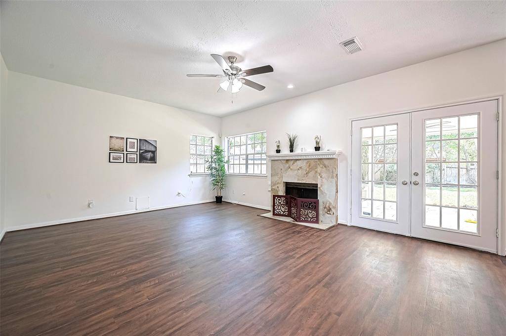 Family room features a Italian Marble Accent Fireplace with French doors opening to a covered patio