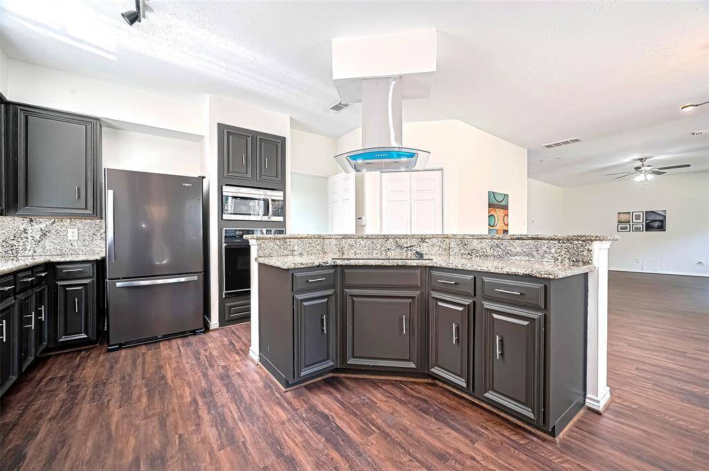 Kitchen island featuring a sleek surface cooktop complemented by a modern ventilation system