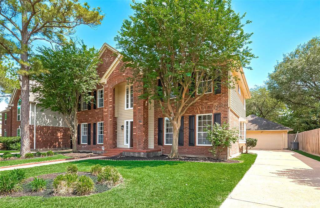 Lush Greenery with mature trees spacious driveway leading to two car garage