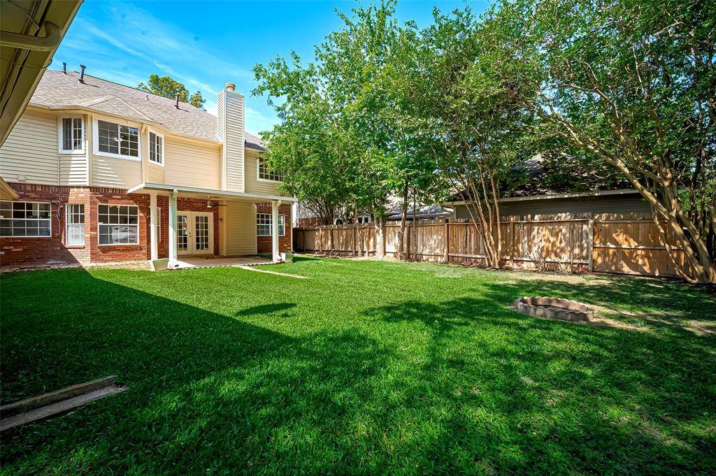Back view of the house featuring a charming patio surrounded by lush greenery